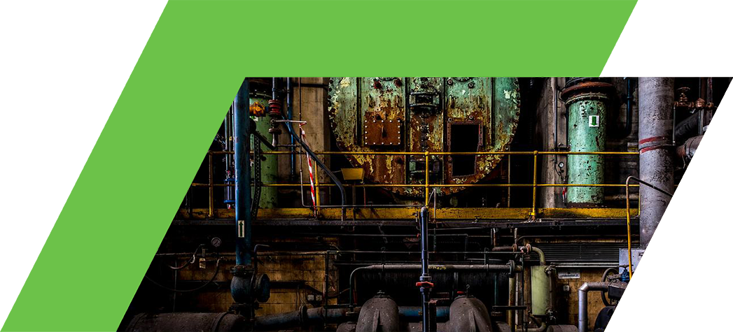 An industrial setting featuring large, rusted machinery and pipes against a dark backdrop.