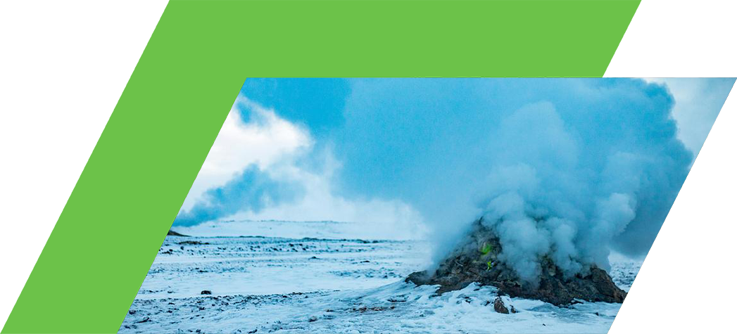 A geothermal vent releases steam and smoke against a snowy landscape under a cloudy sky.