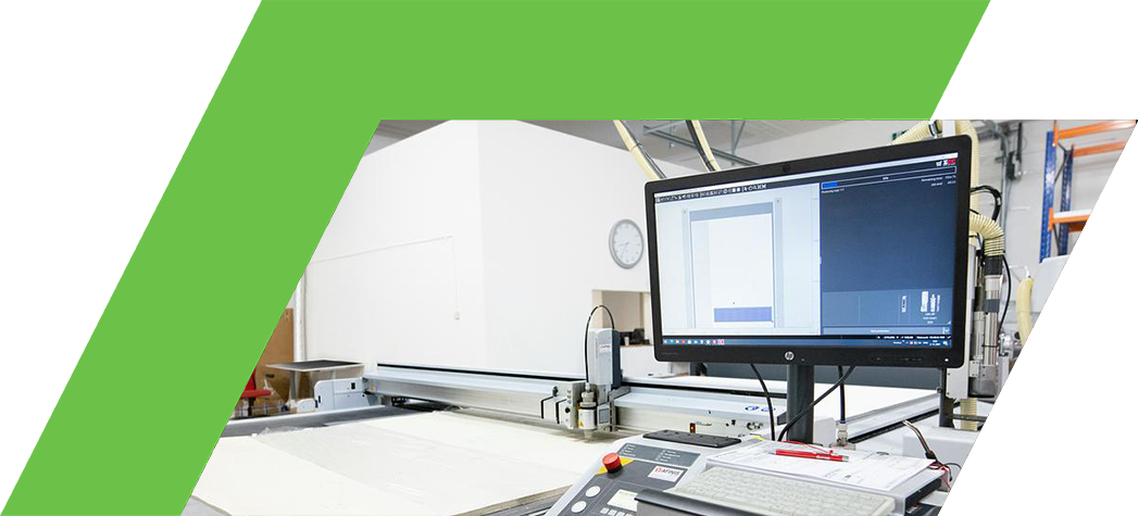 A large cutting machine with a computer monitor and control panel in a workshop setting.